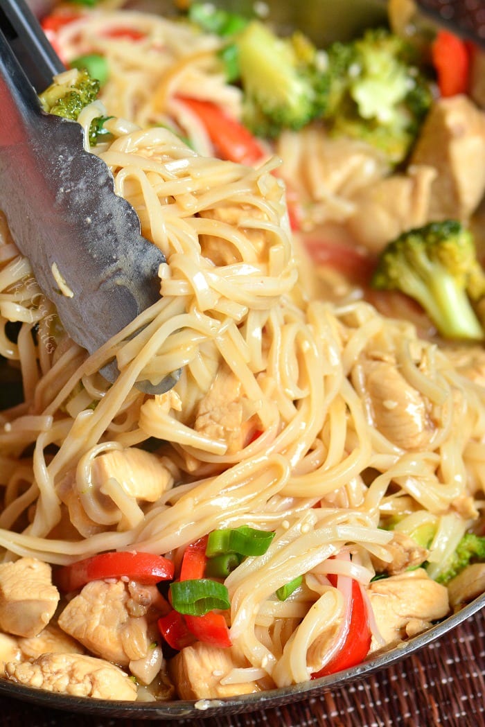 Sesame Chicken Noodles in pan lifting some out with tongs 