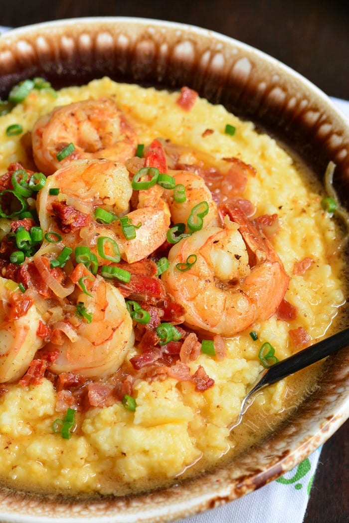Shrimp and Grits is a wonderful southern classic that consists of buttery, cheesy grits topped with juicy shrimp that's been cooked with bacon and sub dried tomatoes. #shrimp #dinner #easydinner #grits