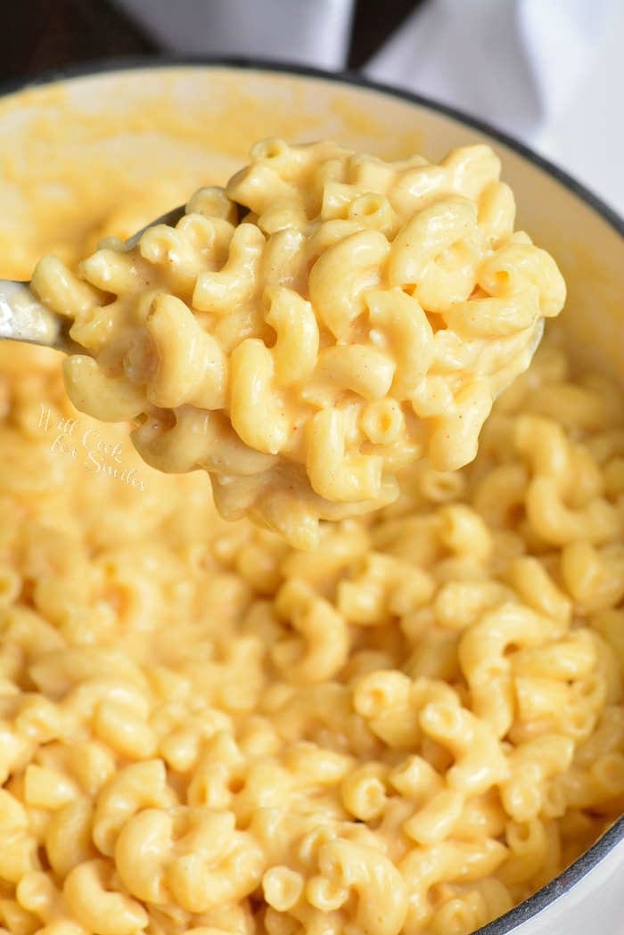 Homemade Mac and Cheese Recipe in a pot being scooped out with a metal spoon 