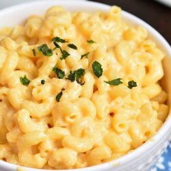 mac and cheese in white bowl with parsley garnish.