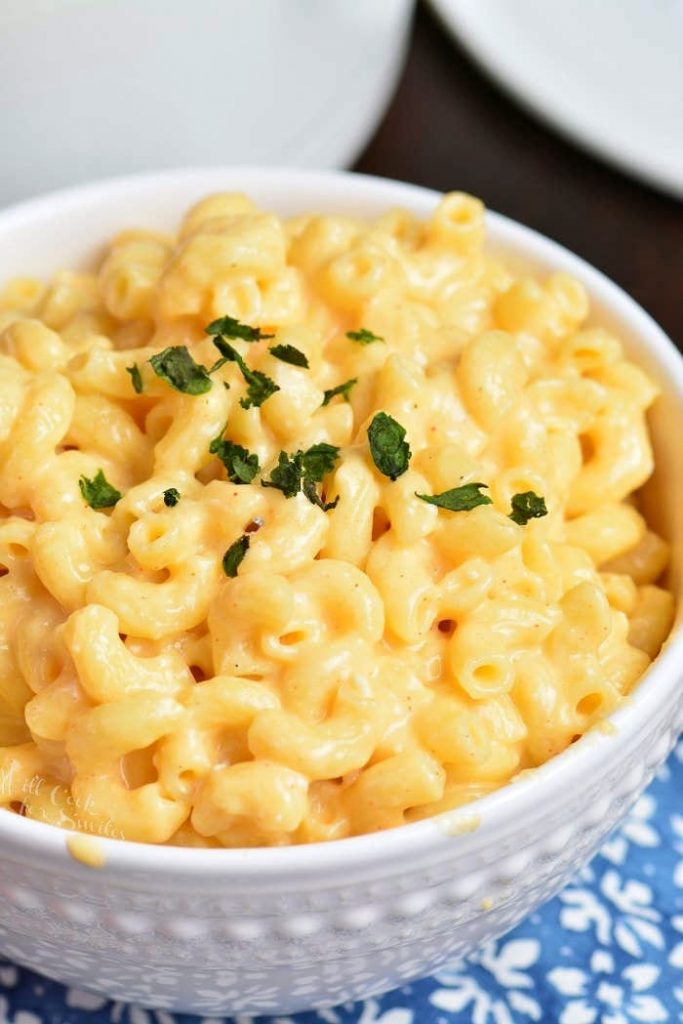 mac and cheese in white bowl with parsley garnish.