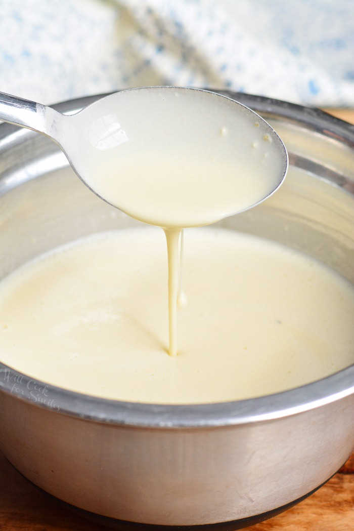 Crepe batter in a metal bowl with a spoon, spooning some out.