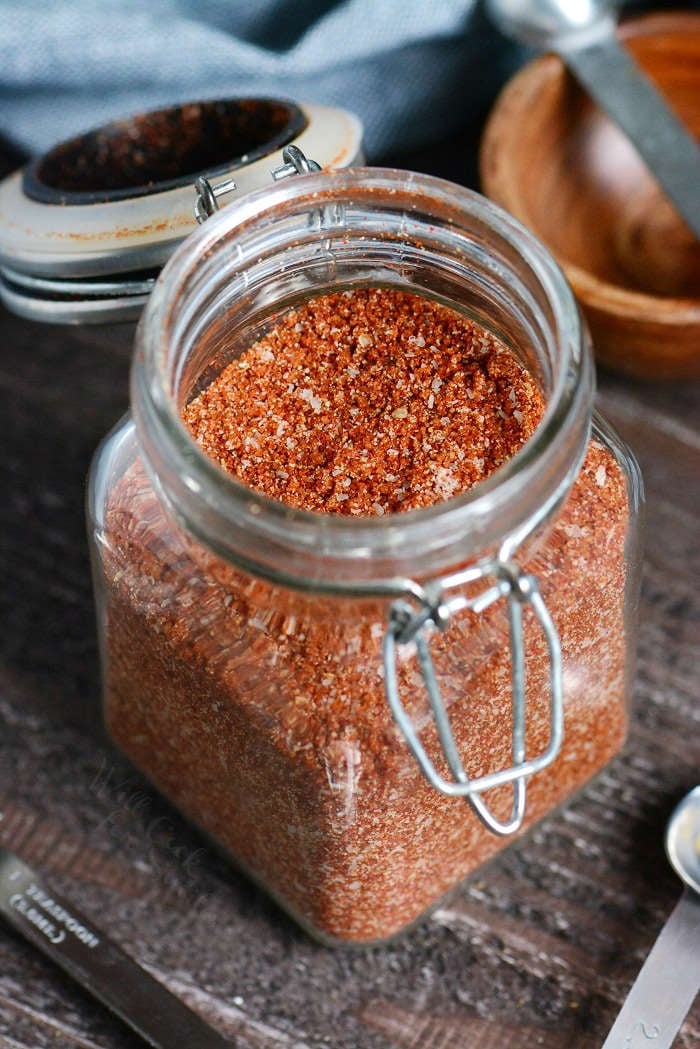 Dry Rub in a glass jar on a wooden cutting board 