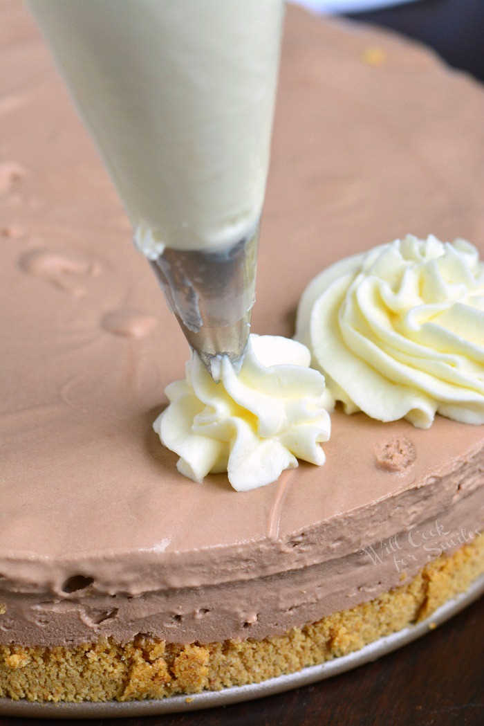 piping whipped frosting onto cheesecake.