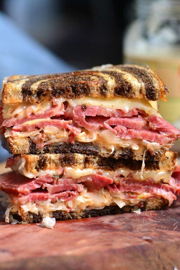 Reuben Sandwich cut in half and stacked on top of each other on cutting board 