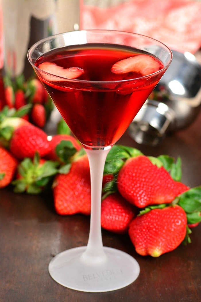 Strawberry Shortcake Martini in a martini glass with sitting on wood table with strawberries 