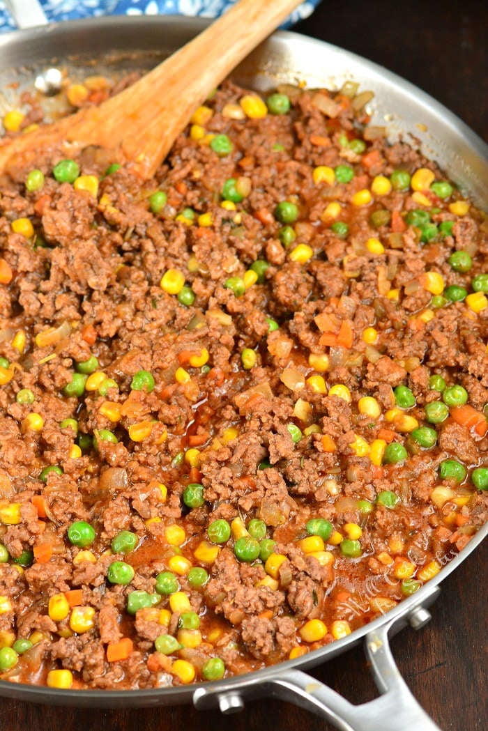 Shepherd's Pie filling being cooked in a pan with a wooden spoon 