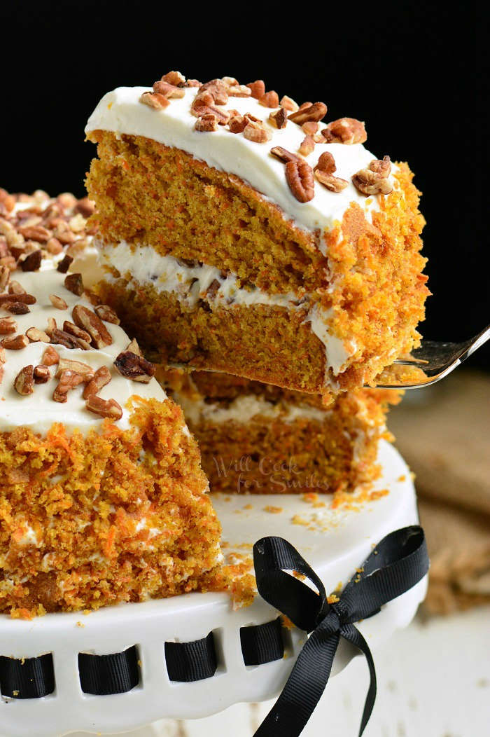 Amazing Carrot Cake on a cake stand with a piece being lifted out 
