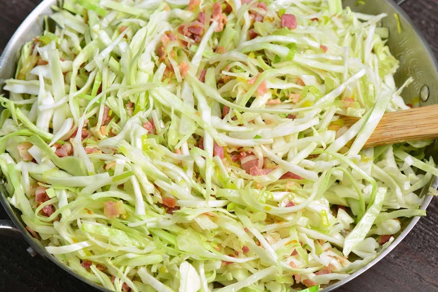 stirring in shaved cabbage into the bacon and leeks.