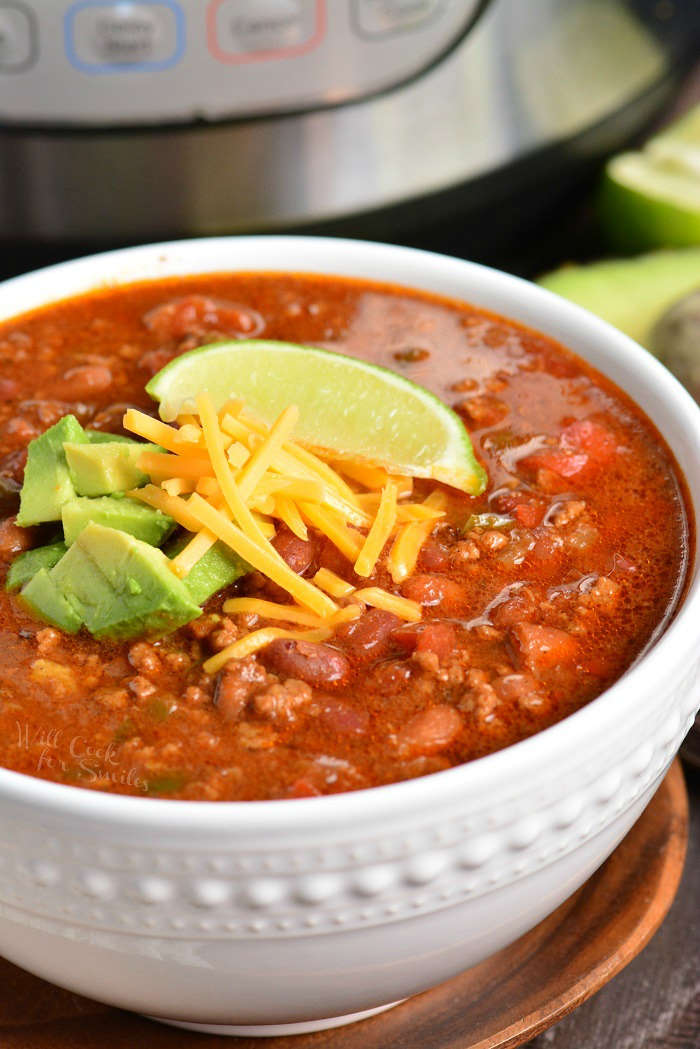 Chili in Instant Pot in a bowl with lime wedge, cheese, and avocado on top