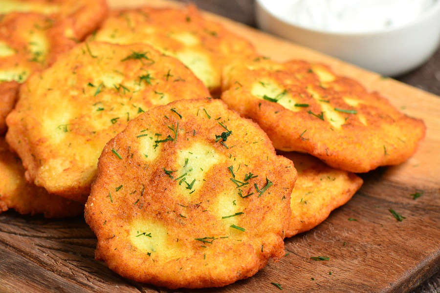 potato pancakes spread across one another on a wood cutting board.