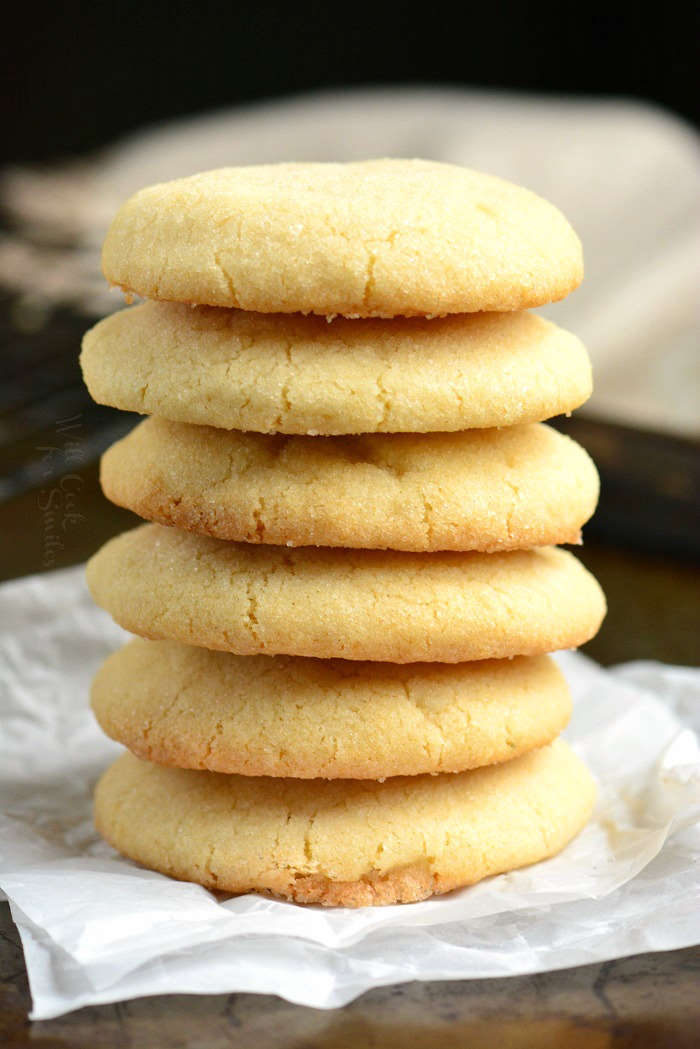 Sugar Cookies stacked up on a wood cutting board 