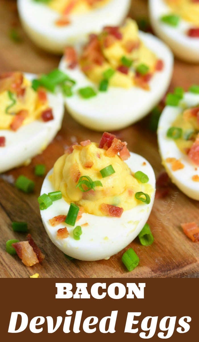 Classic Deviled Eggs with bacon and chives on top sitting on wood cutting board  