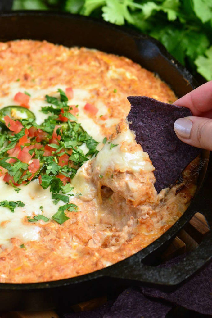 starting to scoop out some refried bean dip with a chip.