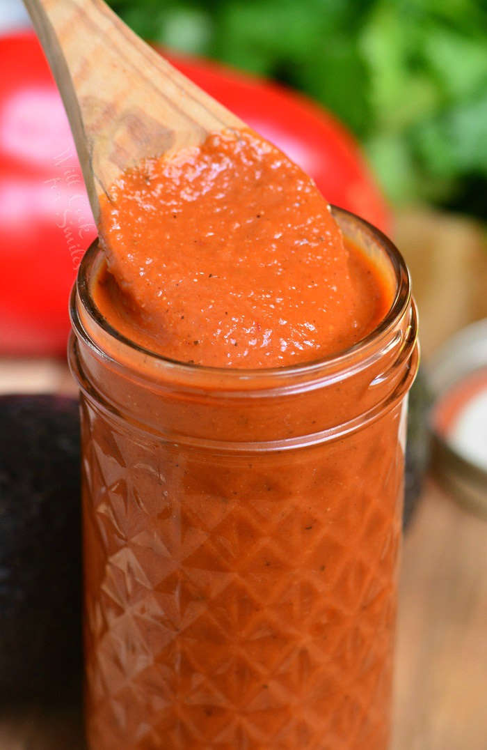 enchiladas sauce in a jar with a wooden spoon 