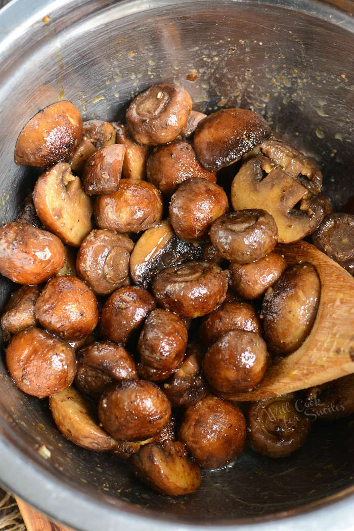 mushrooms with olive oil in a metal bowl with wooden spoon 