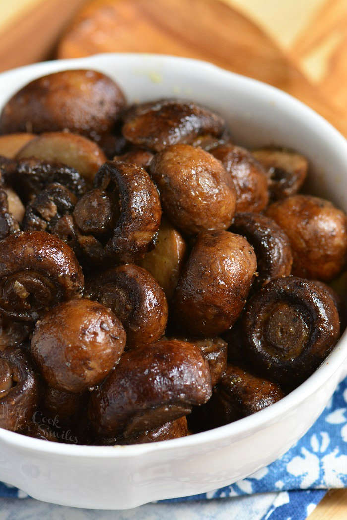 cooked mushrooms in a white bowl on a cutting board