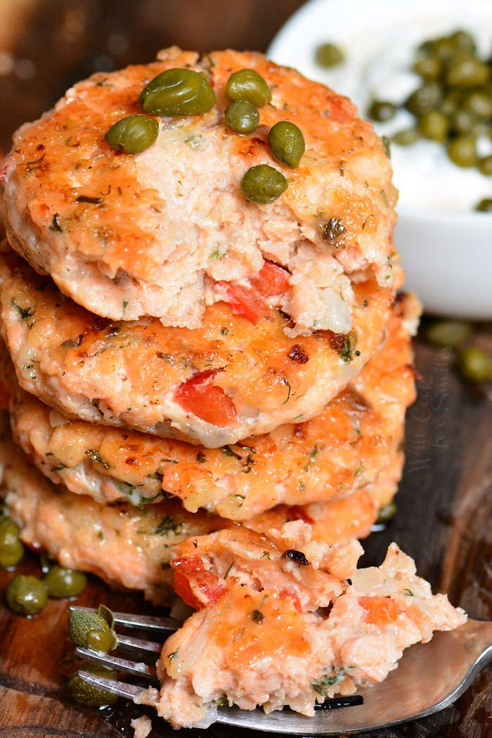 Salmon Patties stacked up on cutting board with capers and a piece on a fork 