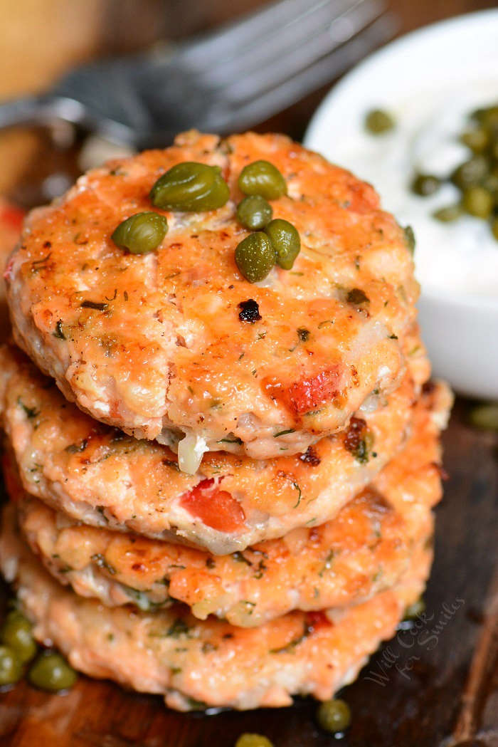 Salmon Patties stacked up on a cutting board 