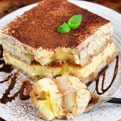 closeup squared view of a slice of tiramisu with piece taken out.