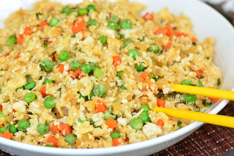 Cauliflower Fried Rice recipe in a bowl with chop sticks 