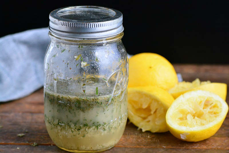 Greek Chicken Mariande in a mason jar on a wood cutting board with lemons 