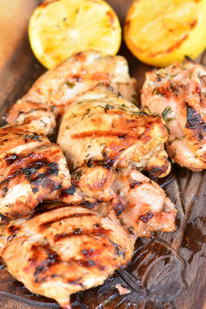 Greek Chicken on a wood cutting board with lemons 