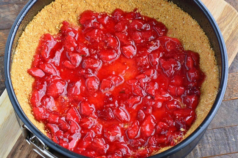 Strawberry filling ontop of graham cracker crust in a spring form pan
