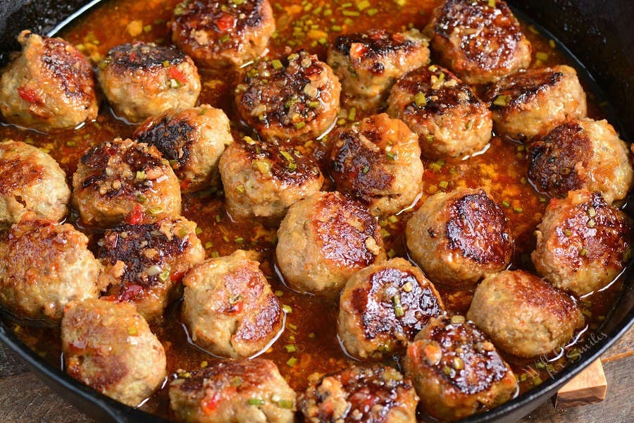 Meatballs in sauce in a cast iron skillet on a wood cutting board 