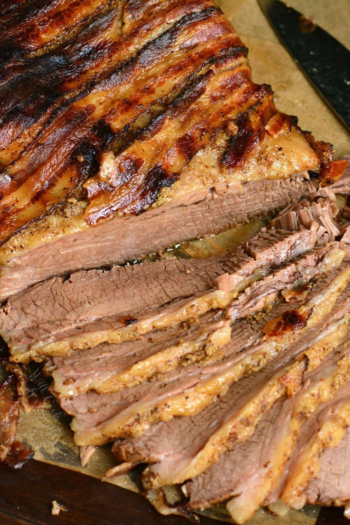 sliced beef brisket on parchment paper on a wood cutting board 