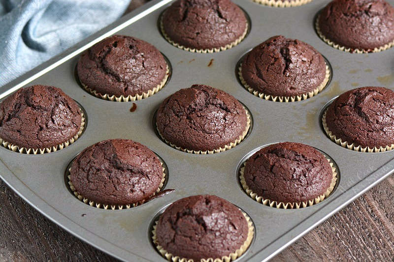  cupcakes de chocolate al horno en bandeja para cupcakes sobre mesa de madera