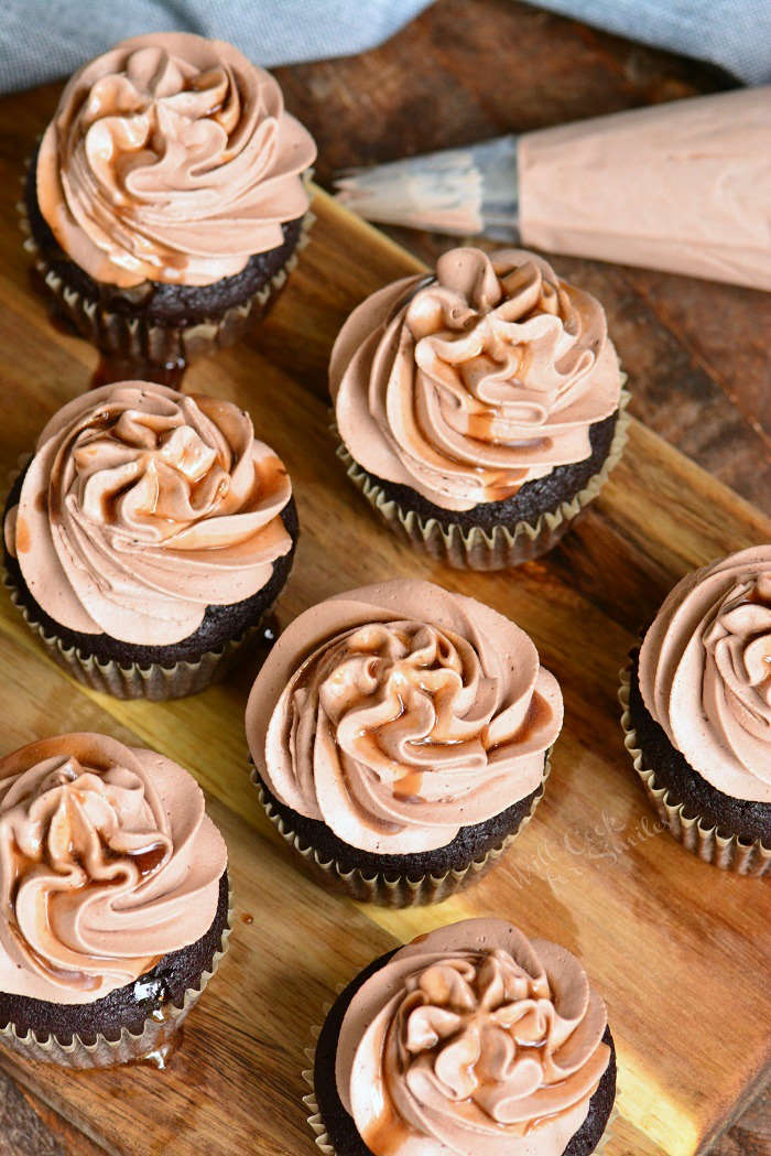 chocolate stout cupcakes on wood cutting board with pastry bag full of frosting