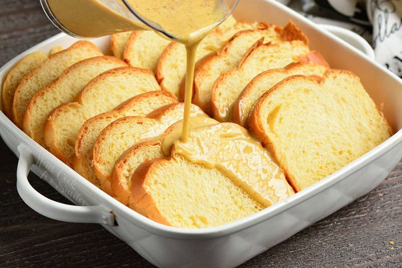 Brioche bread in a casserole dish getting the egg mixture poured over it 