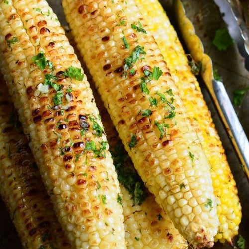browned corn on the cob with parsley on top 