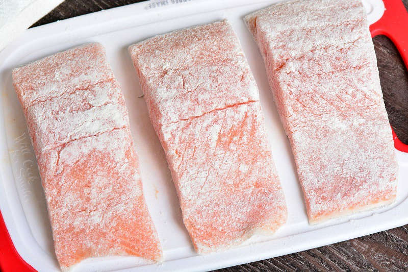 lightly dusted salmon with flour on a plastic cutting board 