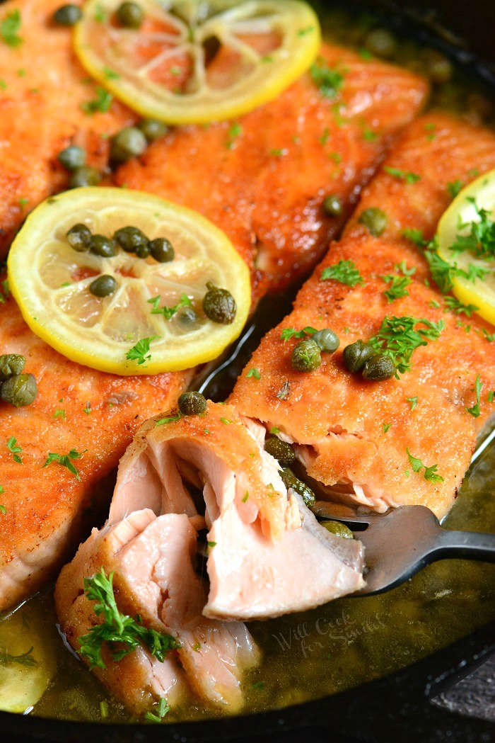 salmon piccata with lemon and capers in a cast iron skillet 