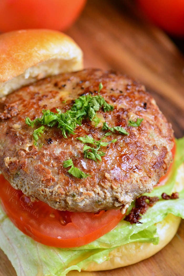turkey burger on Brioche bun with lettuce and tomato on a wood cutting board 
