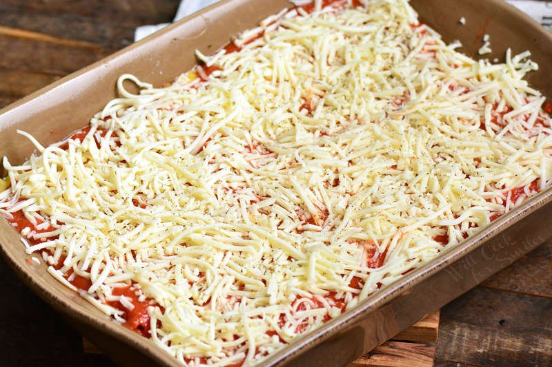 uncooked vegetable lasagna in a casserole dish with cheese on top 