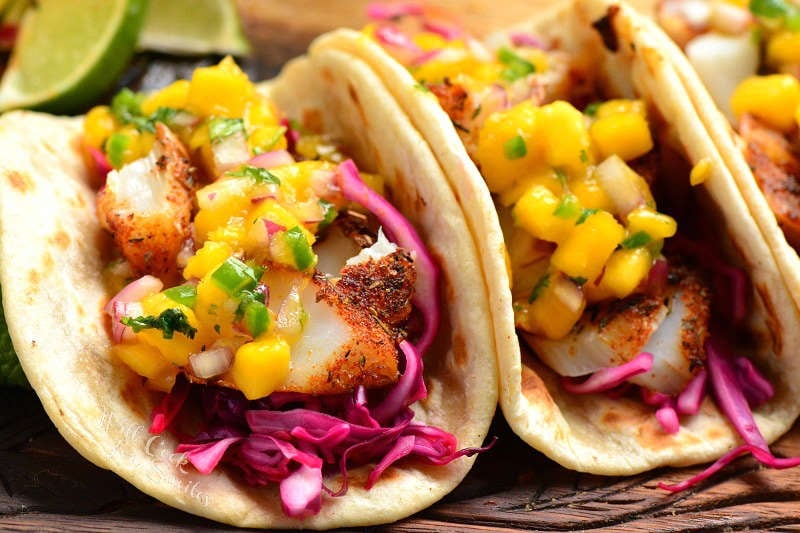 fish tacos with mango salsa on a wooden cutting board 
