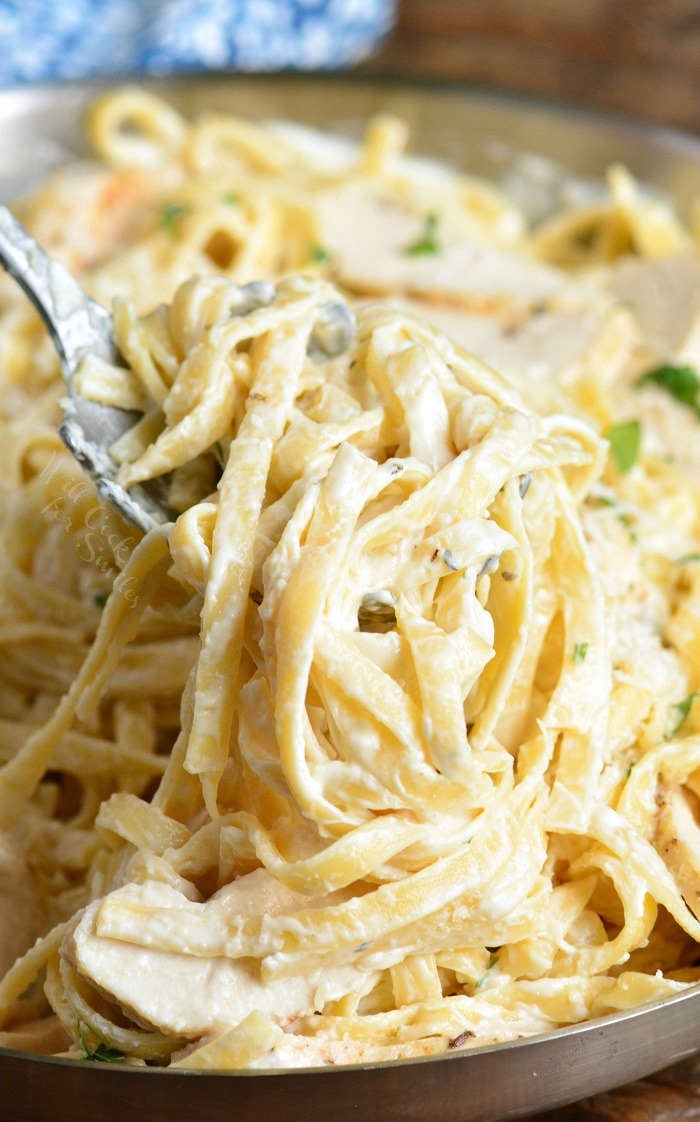 spooning cooked pasta in the chicken fettuccine alfredo
