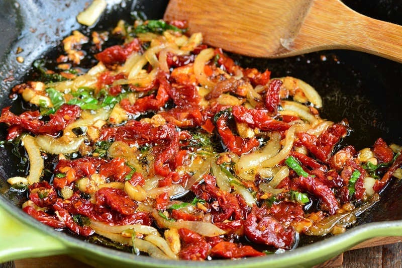 cooking veggies in the same pan with a wooden spoon 