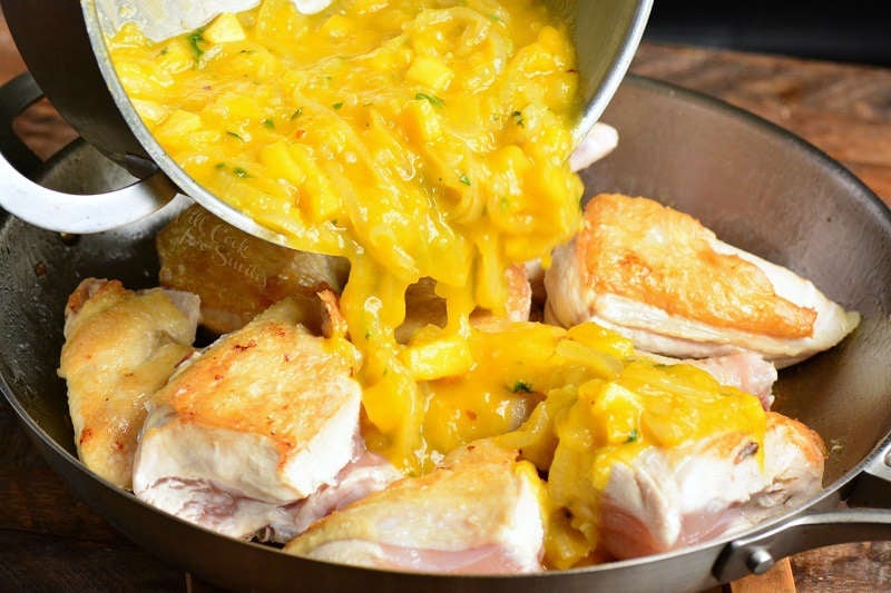 pouring mango over chicken into the pan 