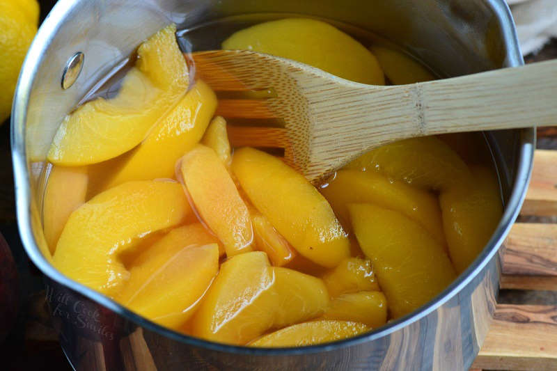 Peaches in a pot with a wooden spoon 