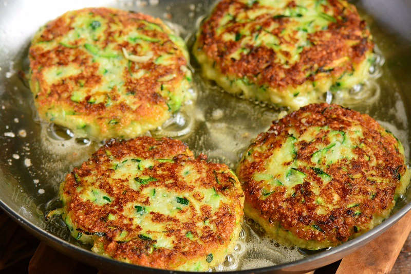 cooking zucchini fritters in a pan with oil