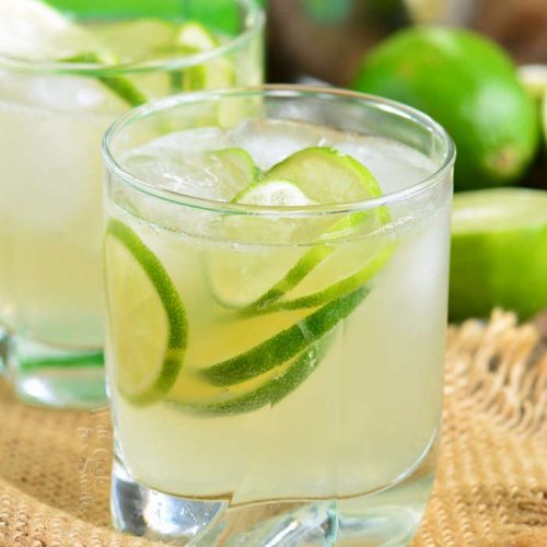 drink in a short glass with ice and sliced limes on a piece of burlap 