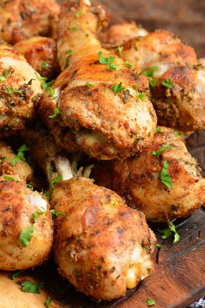 baked chicken drumsticks stacked on a wooden cutting board