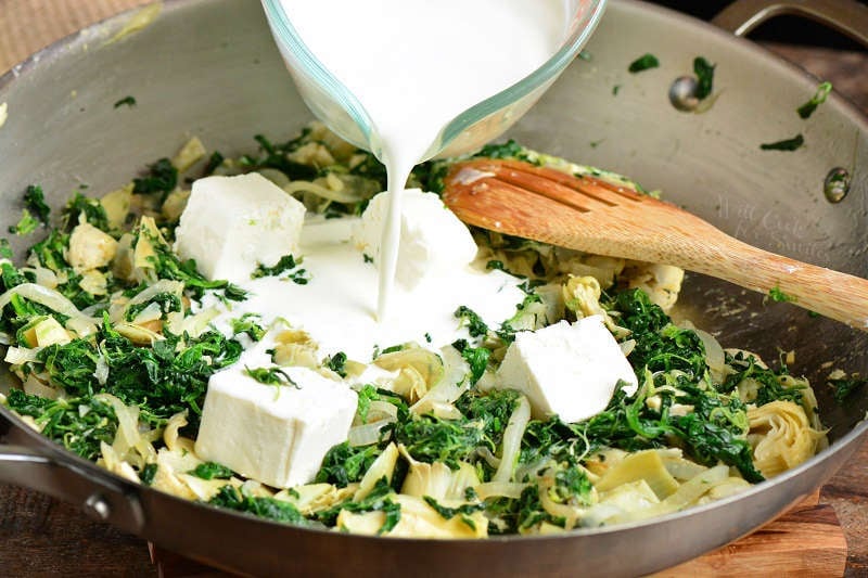 pouring cream into spinach to make a cream sauce