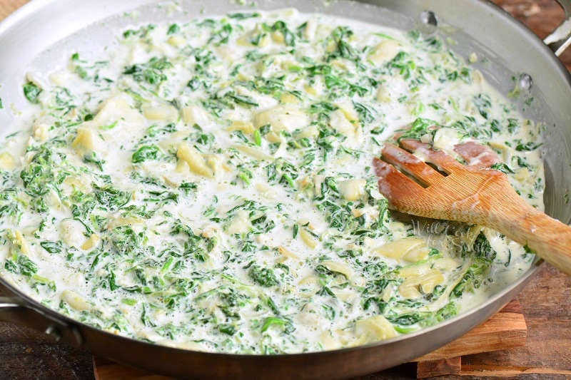 spinach cream sauce in pan with wooden spoon 