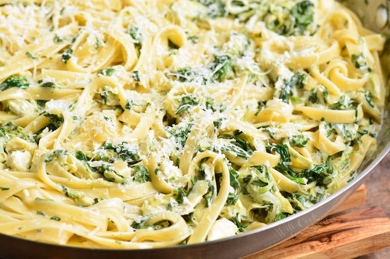 spinach artichoke fettuccine pasta with cheese in a pan