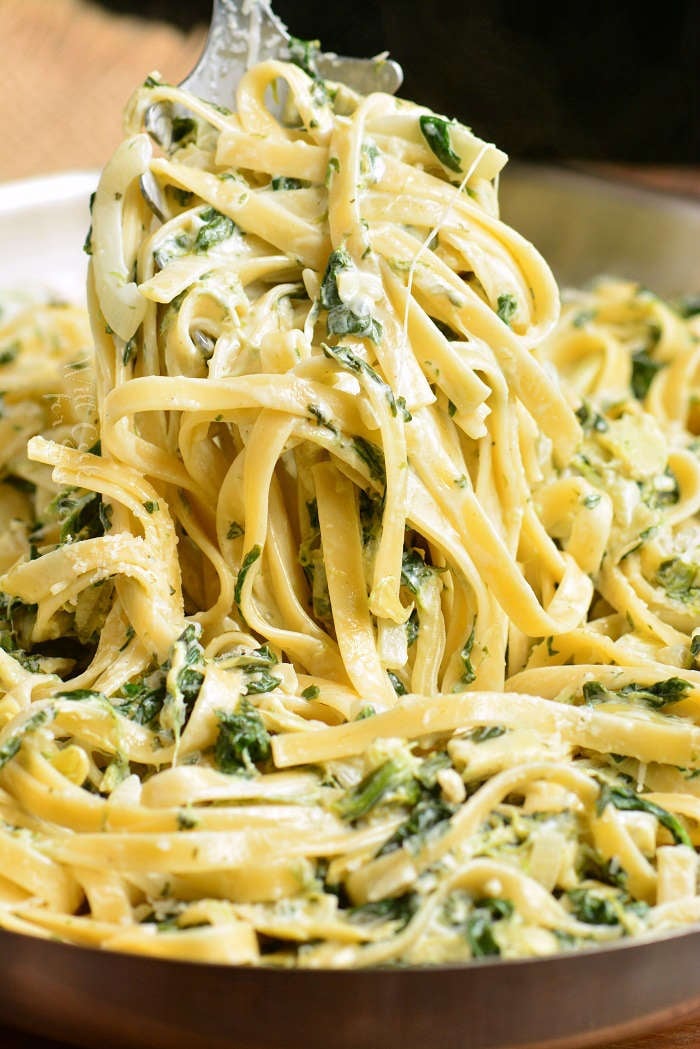 fettuccine being picked up by fork out of a pan 